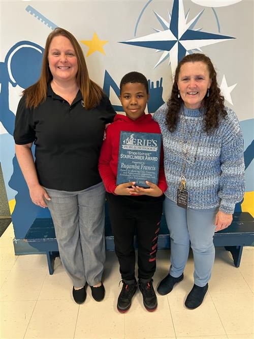 Rugamba Francis, Perry's Stairclimber recipient for January, poses with school staff and his plaque.